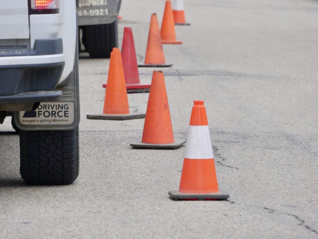 Cam-Trac service vehicles lined along a road with safety pylons marking the work area