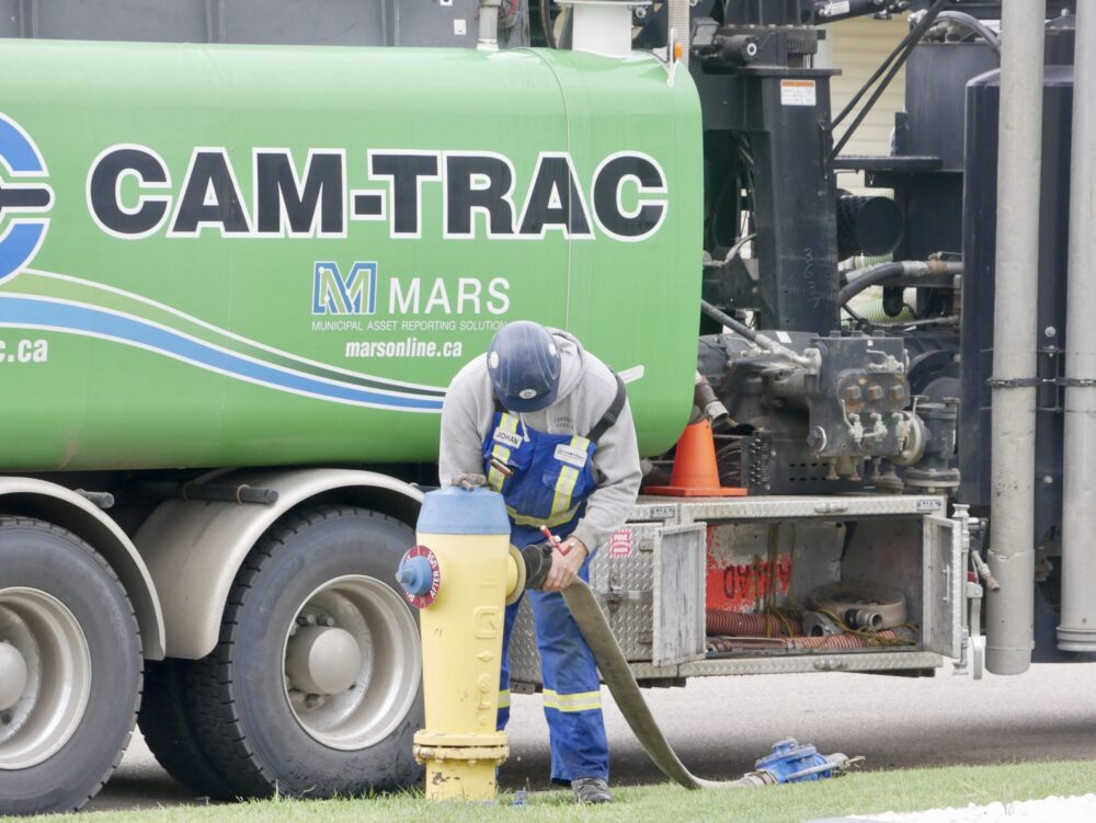 Field worker attaching a hose to a hydrant at a job site