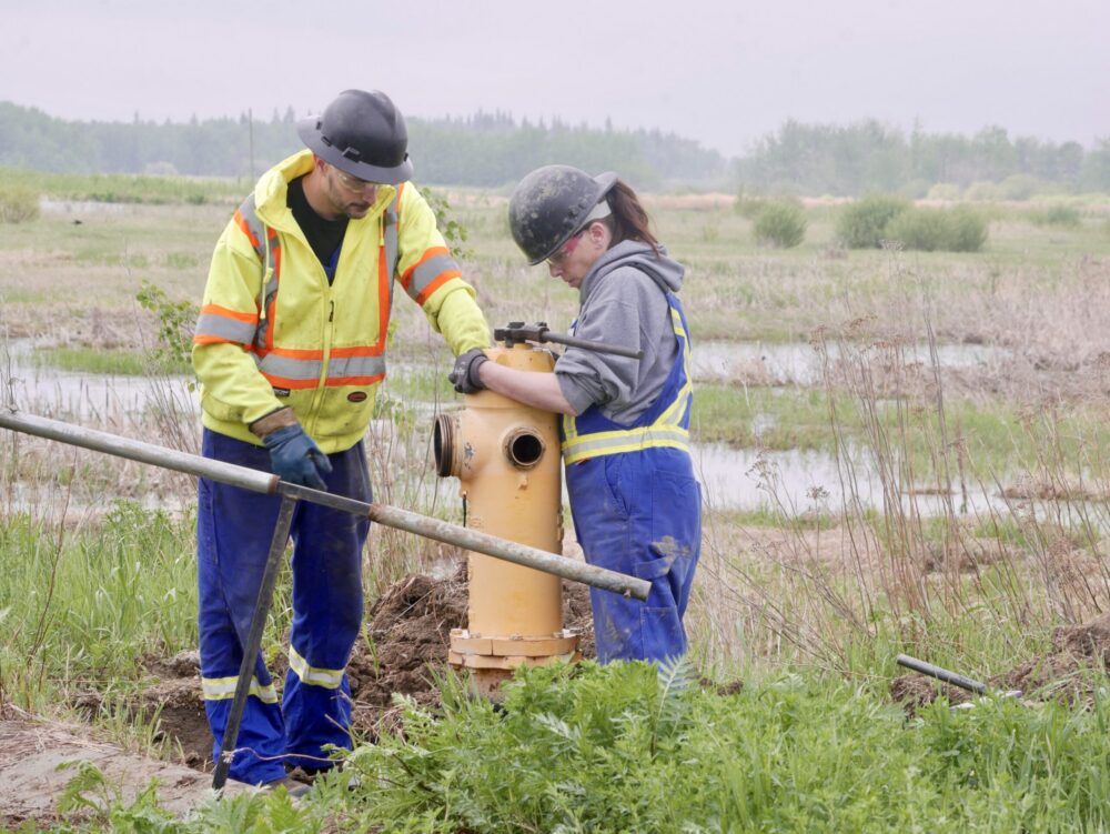Two Cam-Trac field workers servicing a hydrant at a field site