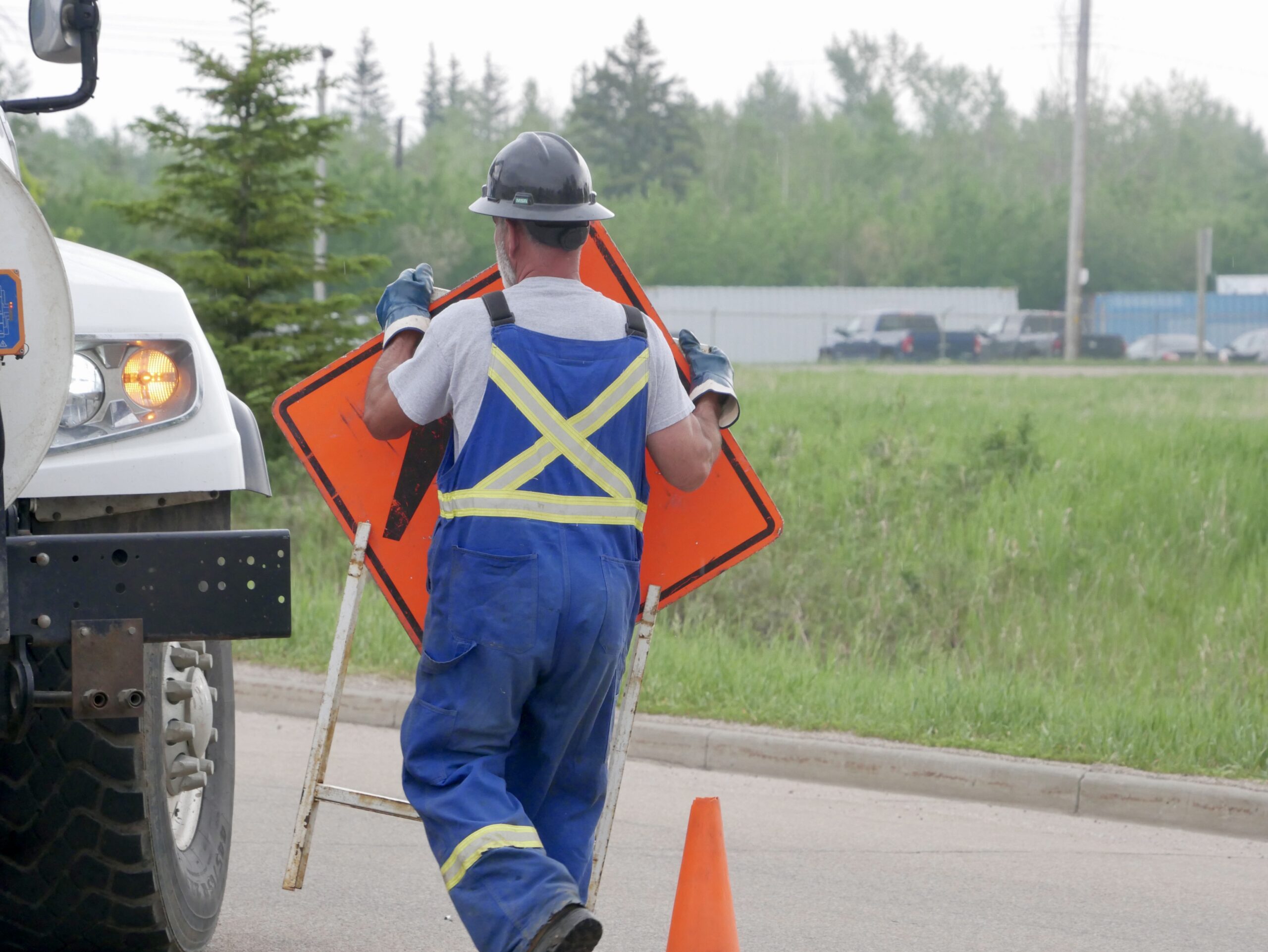 Field worker placing a ‘Person Working’ sign on a roadway