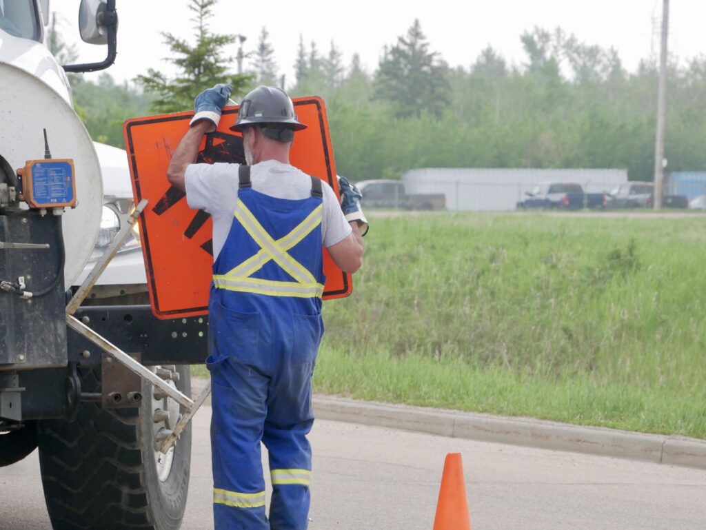ield worker placing a ‘Person Working’ safety sign at a job site