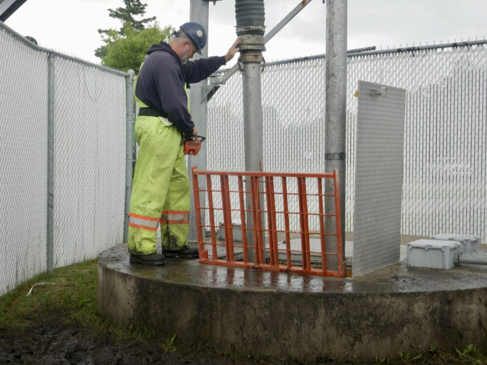Worker performing lift station cleaning inside a wet well or pump station using specialized equipment