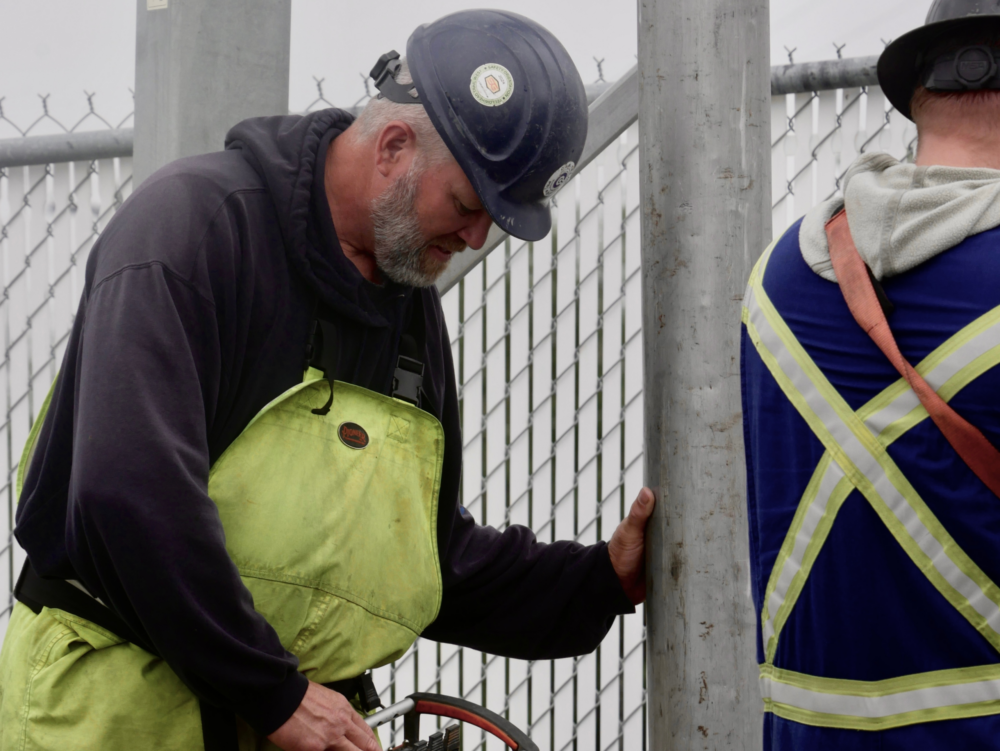 Cam-Trac worker performing water and sewer flushing work at a job site using specialized equipment.