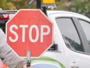Hand holding a stop sign for traffic control and worksite safety